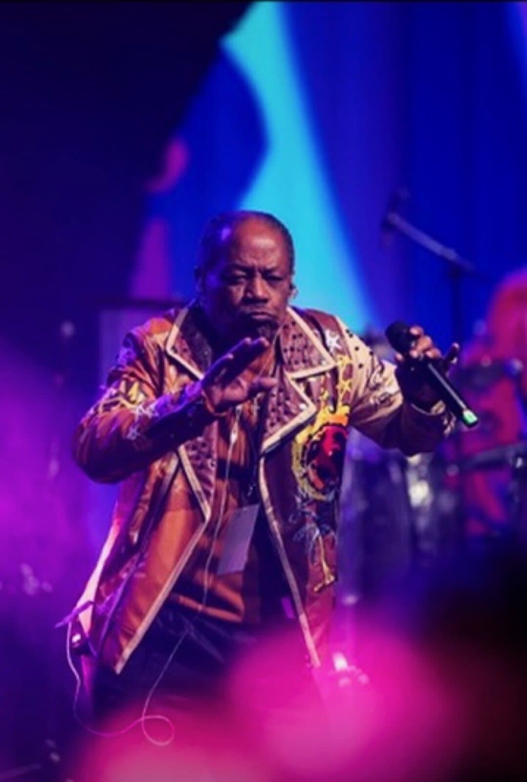 Lawrence Dopson performing in a gold jacket under stage lights