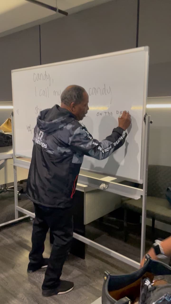 Lawrence Dopson writing lyrics on a whiteboard during class